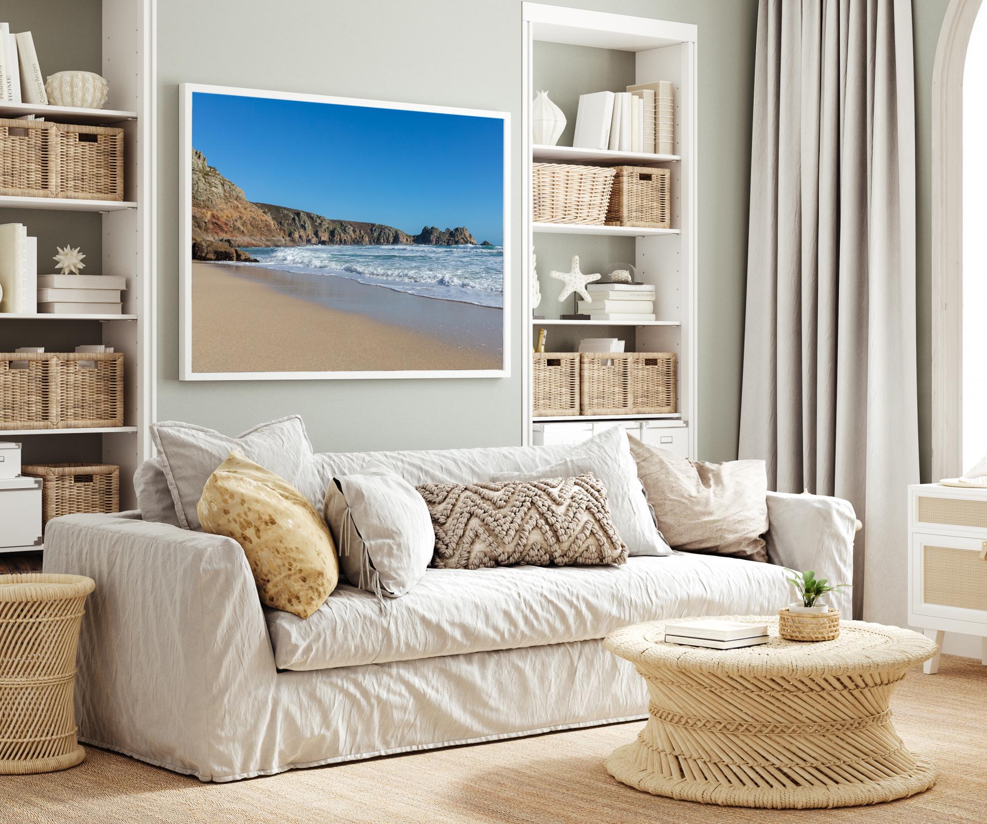 View of Porthcurno Beach at the waters edge with the cliffs on the left hand side and the sea on the right, blue skies and sunny day. Liane Ryan Photography